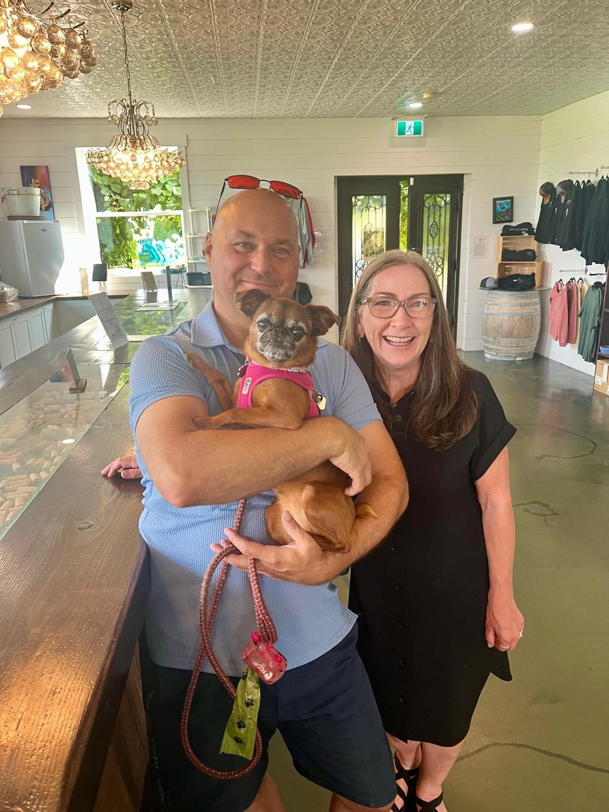 Katy's family smiling with one of their dogs inside a dog-friendly Southeast Kelowna winery